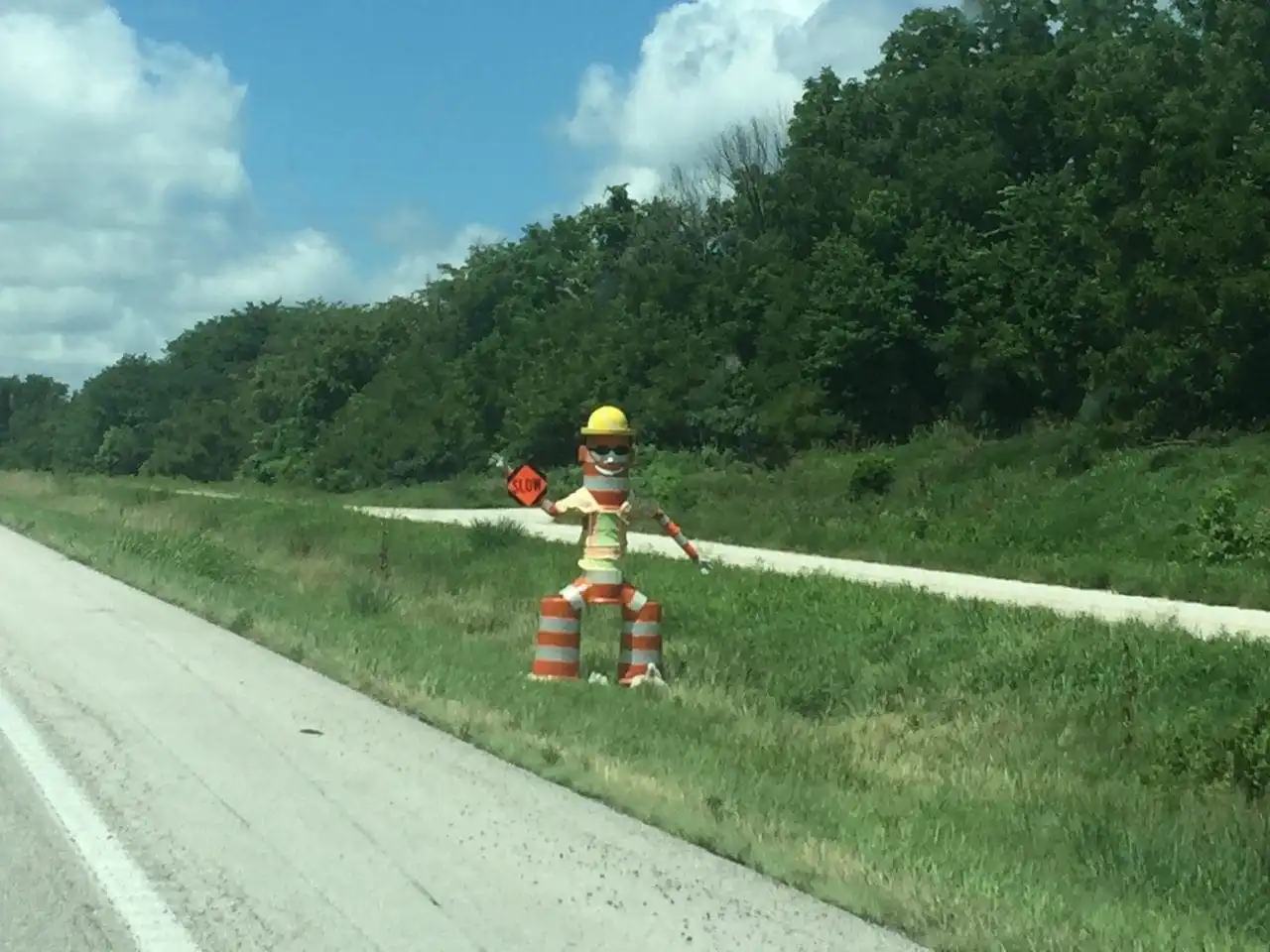 A construction worker sculpture made from orange barrels