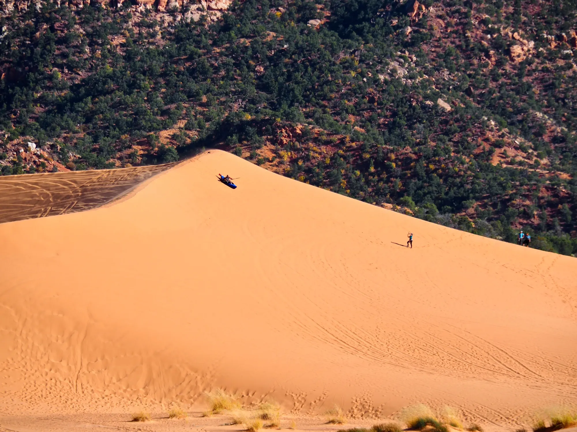 Someone is attempting to kayak down a large sand dune