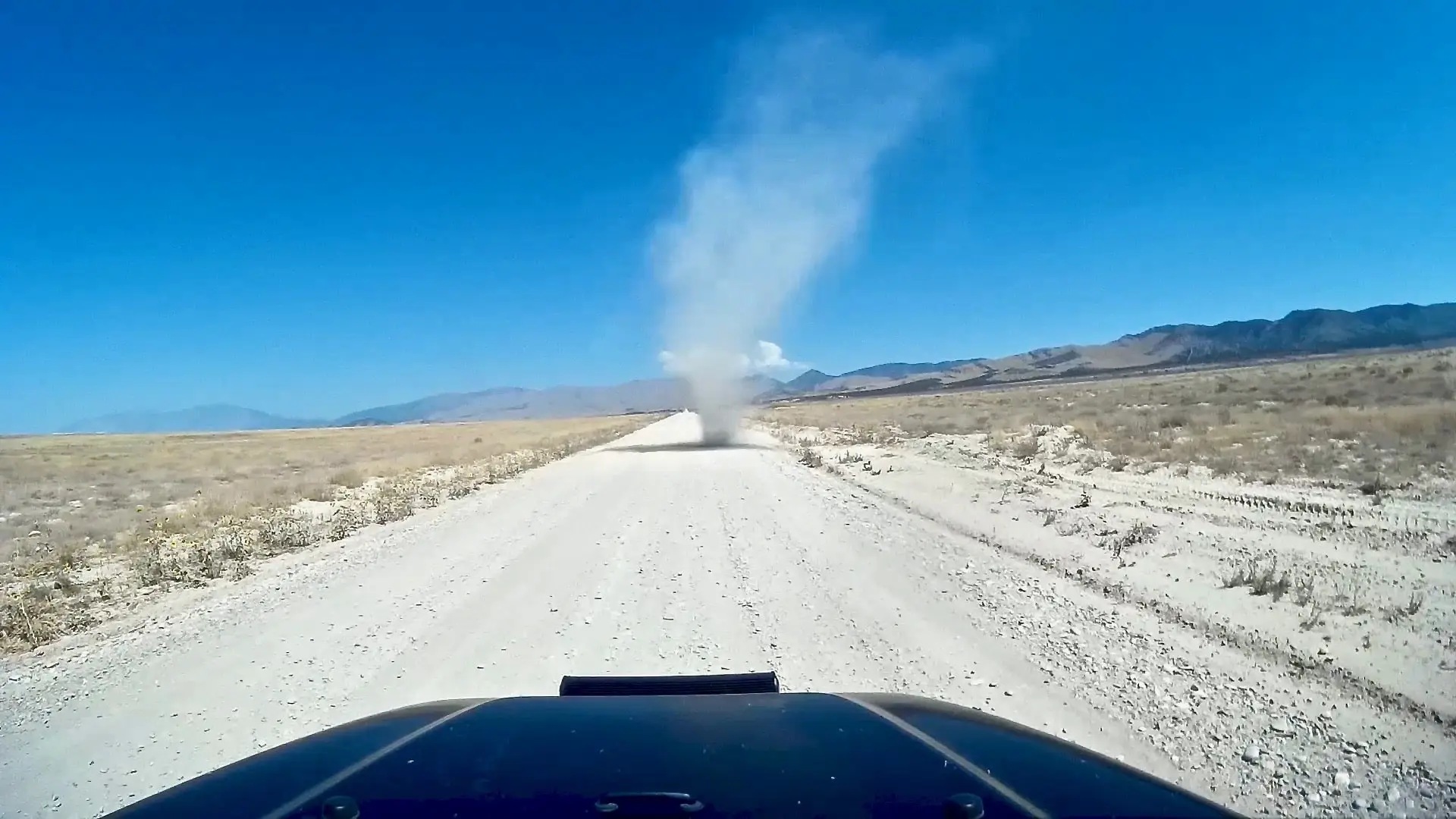 A large dust devil spins up on the road in front of our Jeep