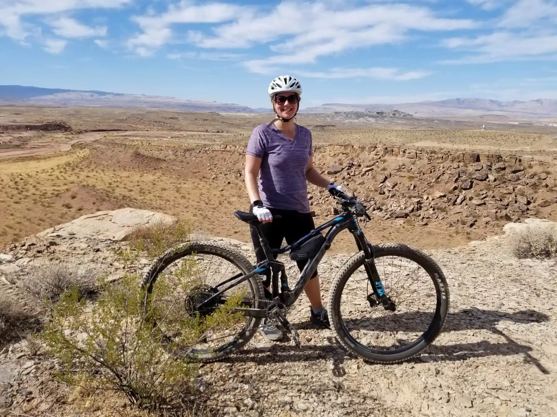 Lindsey is standing with her mountain bike at the top of the Desert Canyons Trail System 