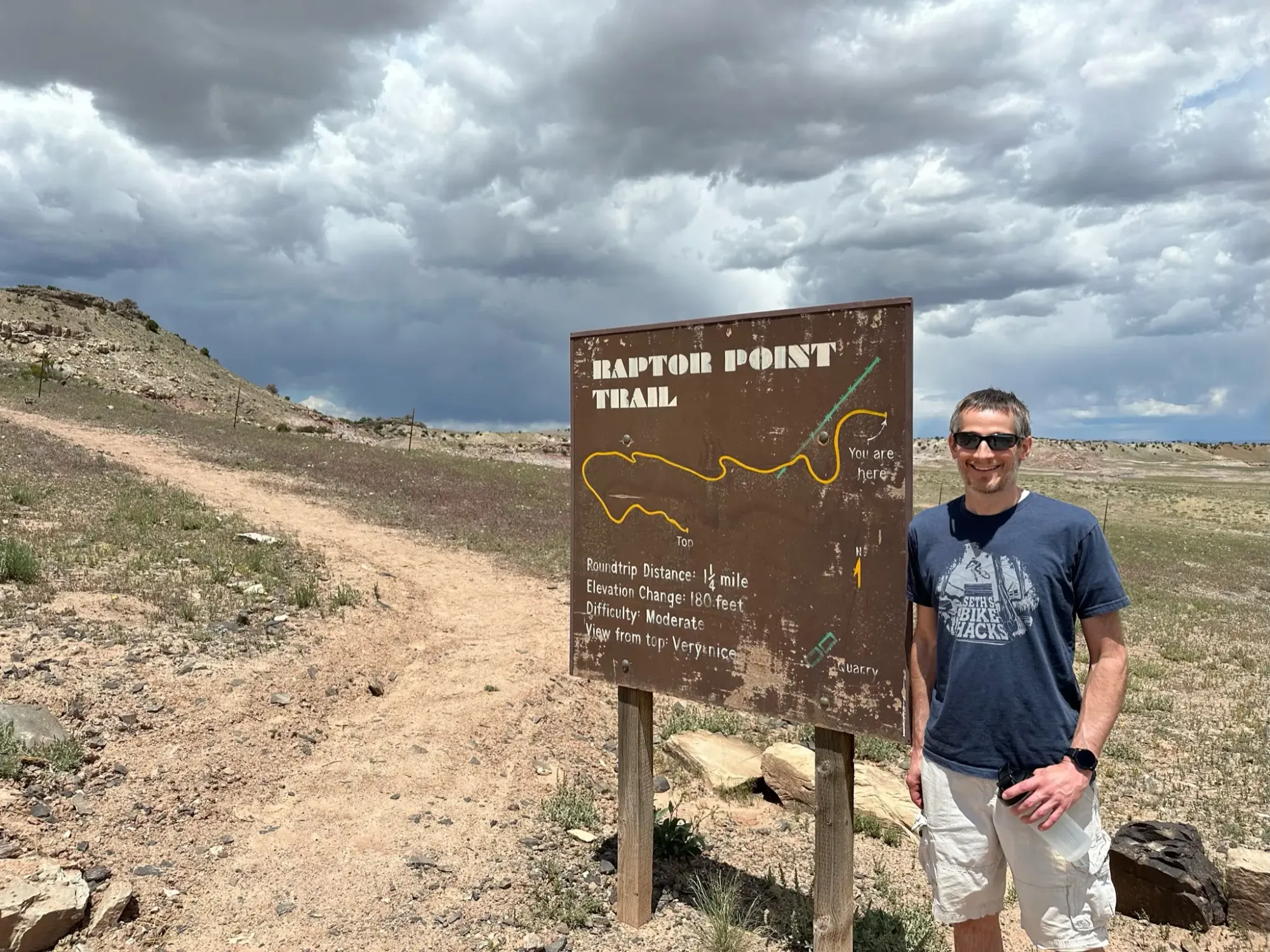 Keith is standing next to the trail sign for the Raptor Point Trail