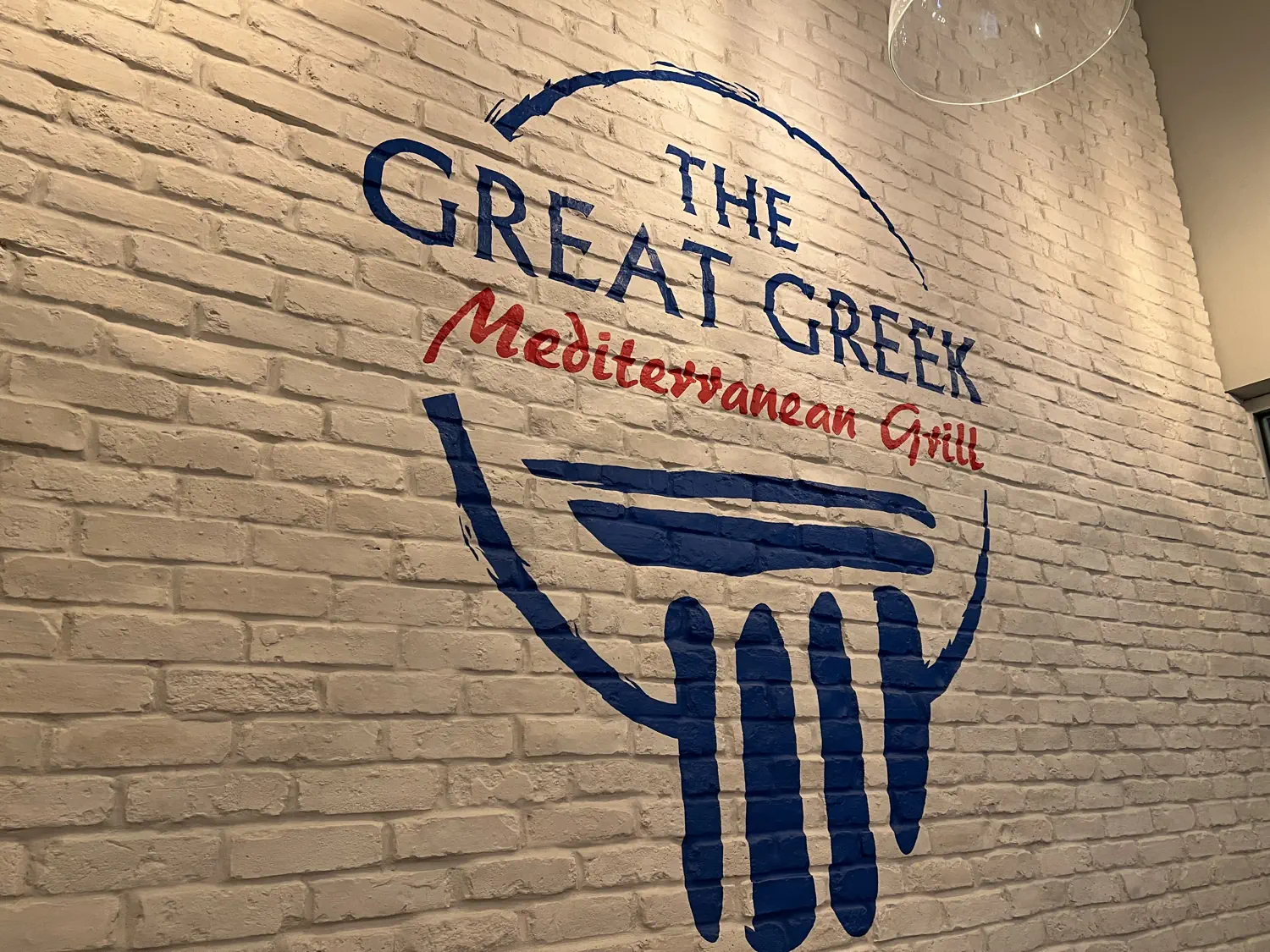 The Great Greek restaurant logo on a brick wall
