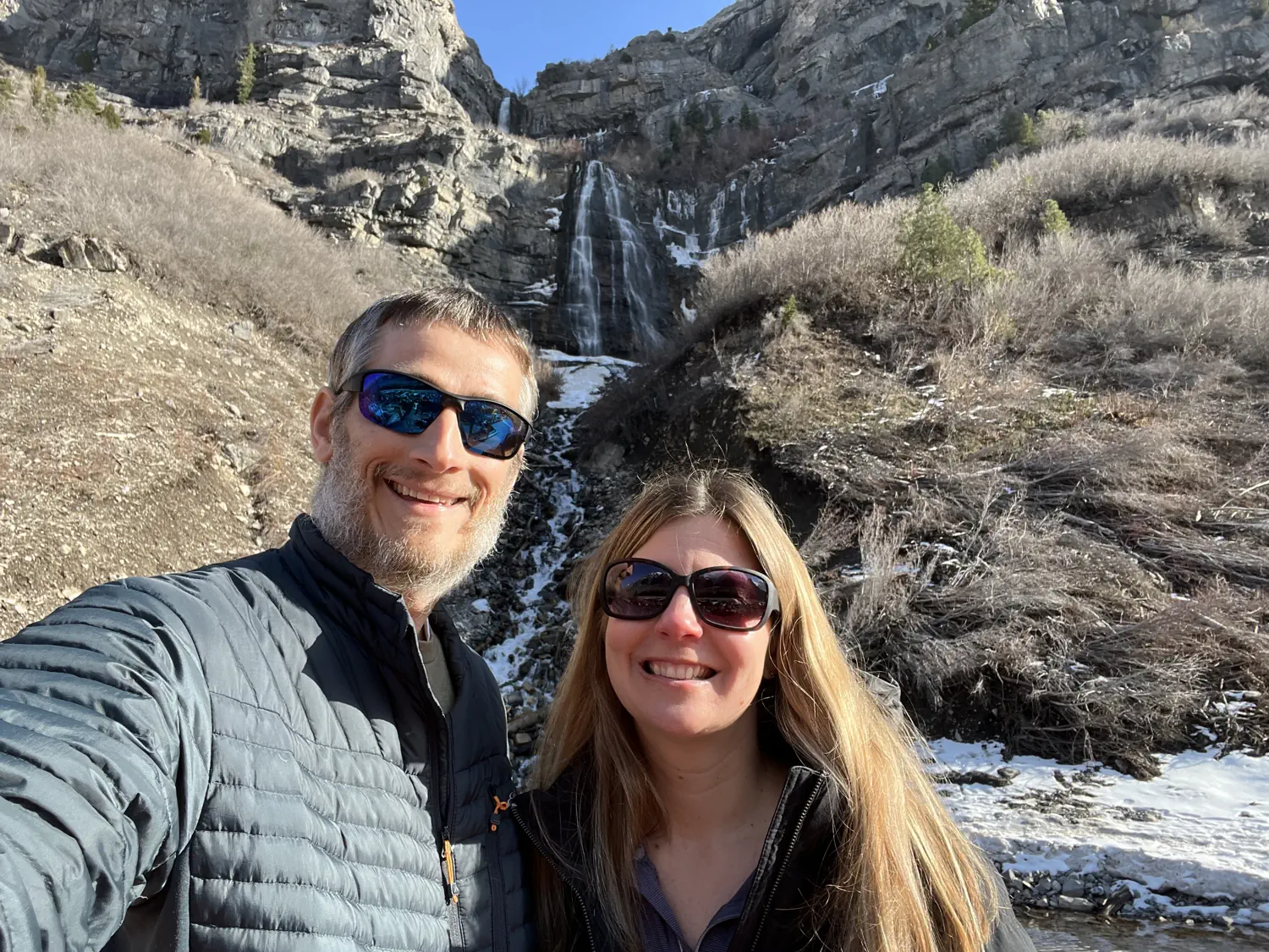 Keith and Lindsey are taking a selfie in front of Bridal Veil Falls in Provo, UT