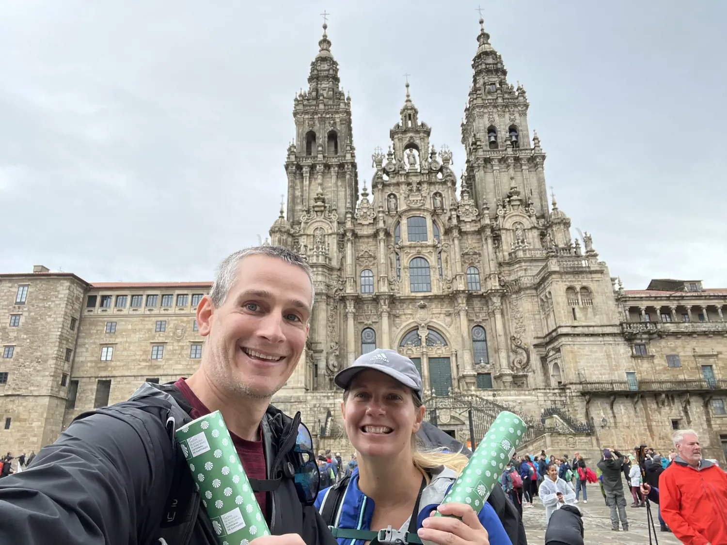 Keith and Lindsey are holding their Camino De Santiago, Portuguese Route completion certificates in front of the Cathedral de Santiago